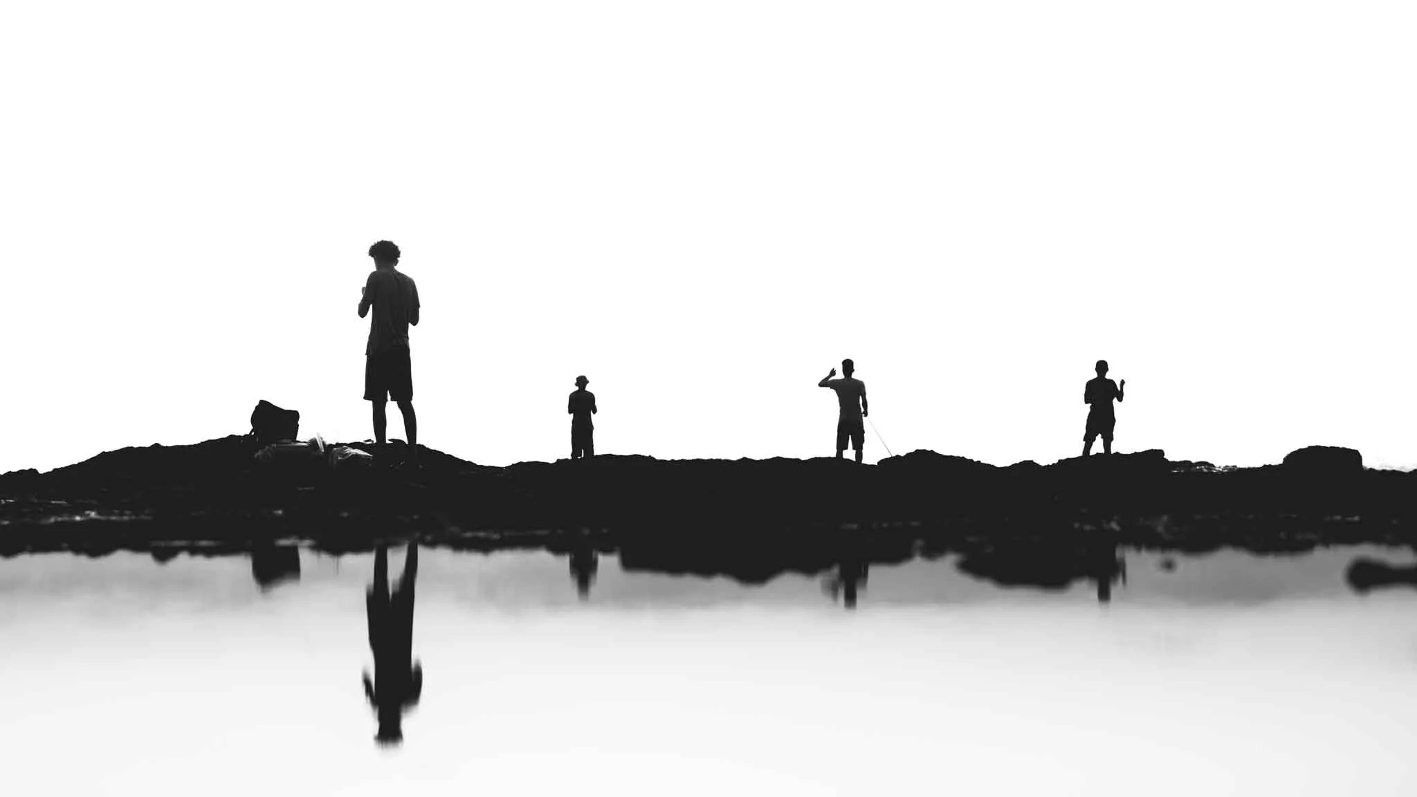 Silhouetted figures on rocky shore
